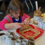 Zoe Hartman, a 3-year-old Islander, makes a bird feeder at Saturday&rsquo;s sustainability fair. Katie Metzger/staff photo