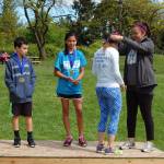 Kai Fulginiti with Mercer Island Parks and Recreation presents Catherine DeHaven with the third place medal at Saturday&rsquo;s Run Like a Girl 5K in Luther Burbank Park. Burke Dine (left) finished second, and Jaya Krauser was first. Katie Metzger/staff photo