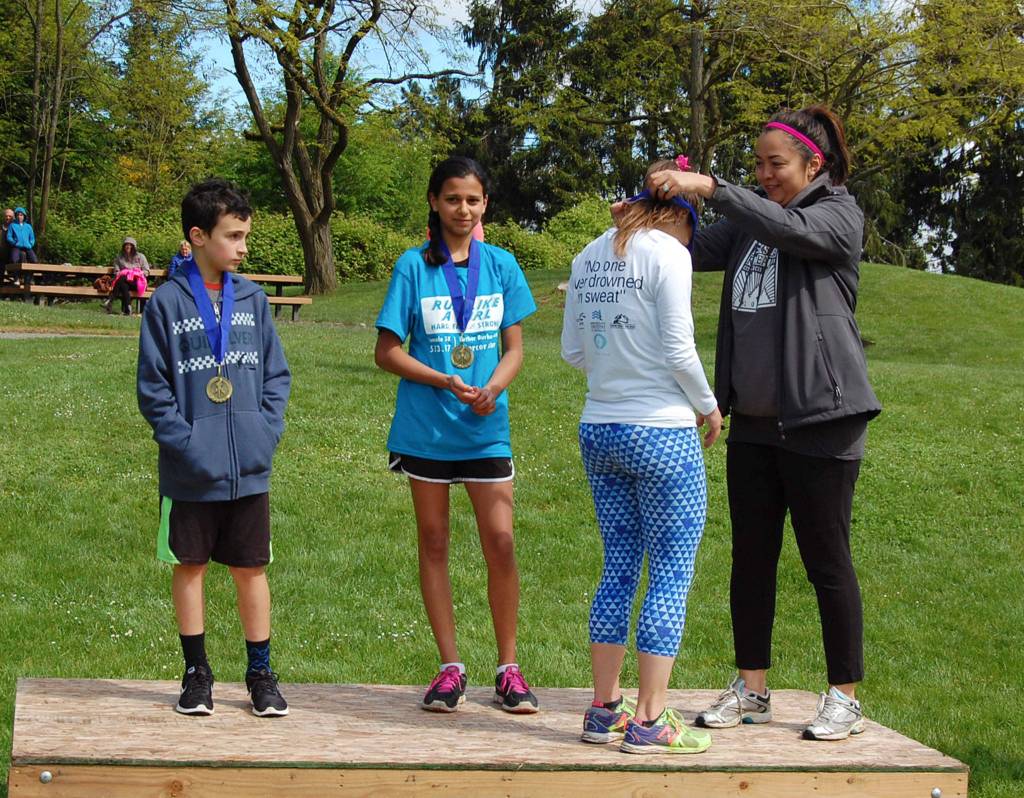 Kai Fulginiti with Mercer Island Parks and Recreation presents Catherine DeHaven with the third place medal at Saturday&rsquo;s Run Like a Girl 5K in Luther Burbank Park. Burke Dine (left) finished second, and Jaya Krauser was first. Katie Metzger/staff photo