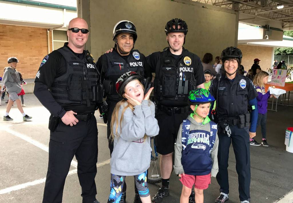 Mercer Island police officers Mike Seifert, Scott Hyderkhan, Robb Kramp and Anna Ormsby pose with kids wearing their helmets on Bike to School Day. Photo courtesy of MIPD