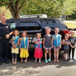 The newest Mercer Island police officer, Alex Rutter (left), provided a tour for a Mercer Island Girl Scout Troop and two little brothers on June 8. At the conclusion of the tour, the kids were good sports and agreed to pose for a picture with Rutter and MIPD Services Commander Leslie Burns. Photo courtesy of MIPD