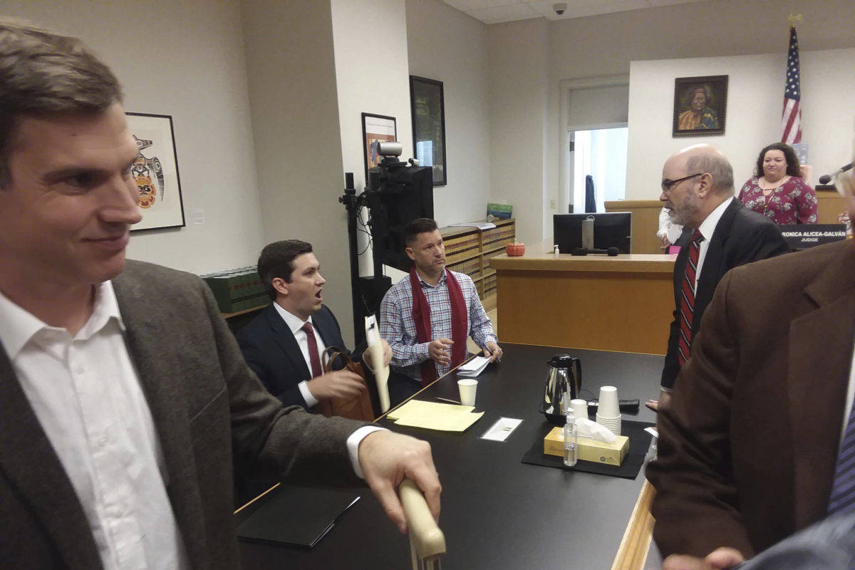 Judge Veronica Alicea-Galván&rsquo;s courtroom just after hearing arguments on the I-27 lawsuit on Friday. From left to right: Mark Cooke of the ACLU-WA; State Rep. Drew Stokesbary, serving as counsel to the defendants; Bothell City Council member and I-27 organizer Joshua Freed; Jeff Slayton, counsel from the Seattle City Attorney&rsquo;s Office; court staff; and the brown-coated shoulder of Dr. Bob Wood, former director of the HIV/AIDS Program at Public Health Seattle/King County. Photo by Casey Jaywork