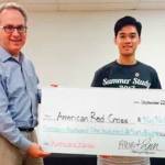 Steven Greimann accepts a check from Albert Lam on behalf of the American Red Cross. Photo via redcrossnw.org