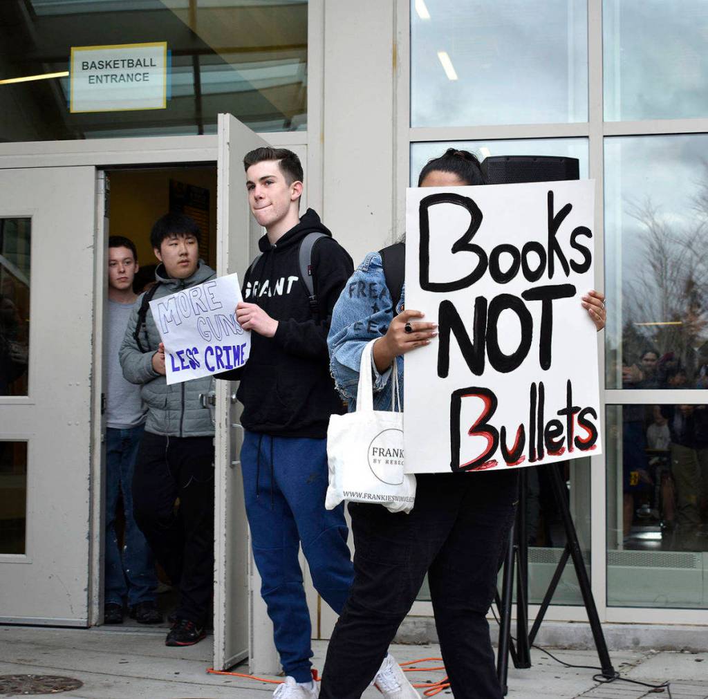 Bellevue High School student Charlie Kern holds a sign calling for more guns, less crime as another student holds a sign that reads books, not bullets. The walkout was student-led and students were able share their opinions and have a dialogue with one another. Raechel Dawson/staff photo