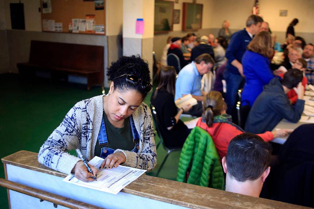 Nashika Hadley fills out a registration form during the 2016 Democratic caucus at the Everett Labor Temple in Everett. (Kevin Clark / Herald file)