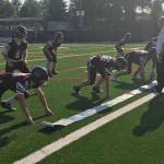 The Mercer Island front seven (linebackers and defensive line) get into their stances while the coaching staff delivers signals and line calls. Shaun Scott/staff photo