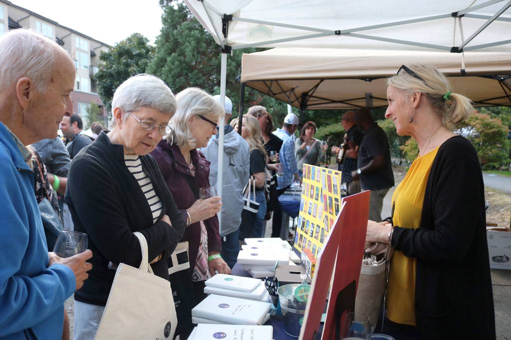 Island Books owner Laurie Raisys talks to customers at Art Uncorked on Sept. 7. Katie Metzger/staff photo