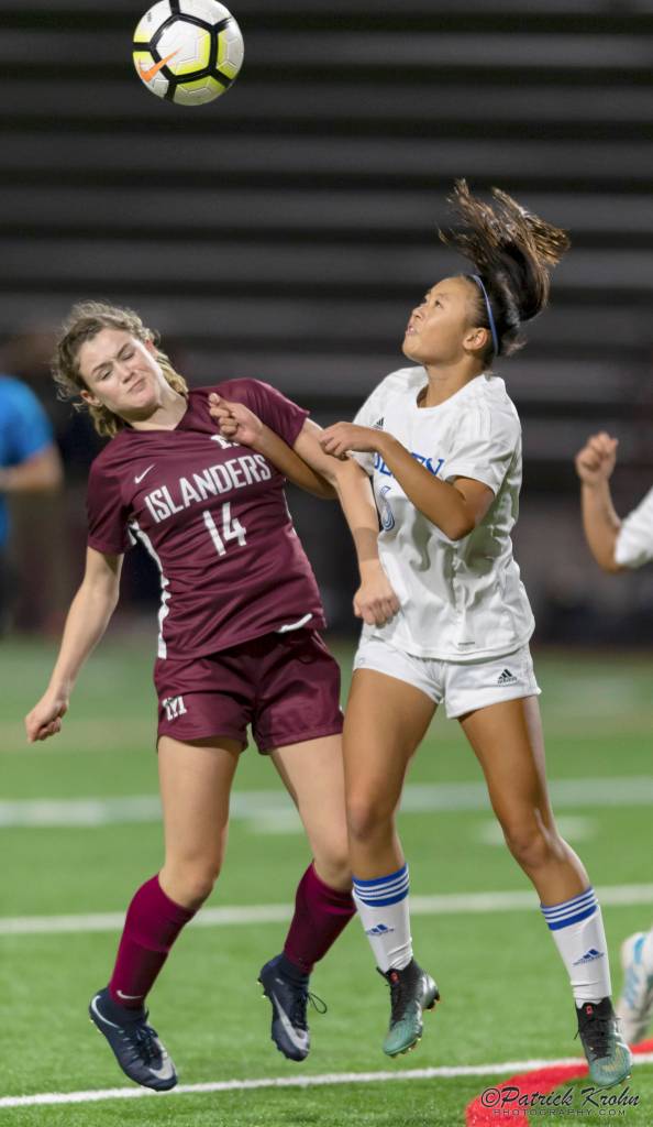 Mercer Island senior Ella Hensey, left, battles with Liberty defender Kelsey Le, right, for possession of a 50/50 in the air. Photo courtesy of Patrick Krohn/Patrick Krohn Photography