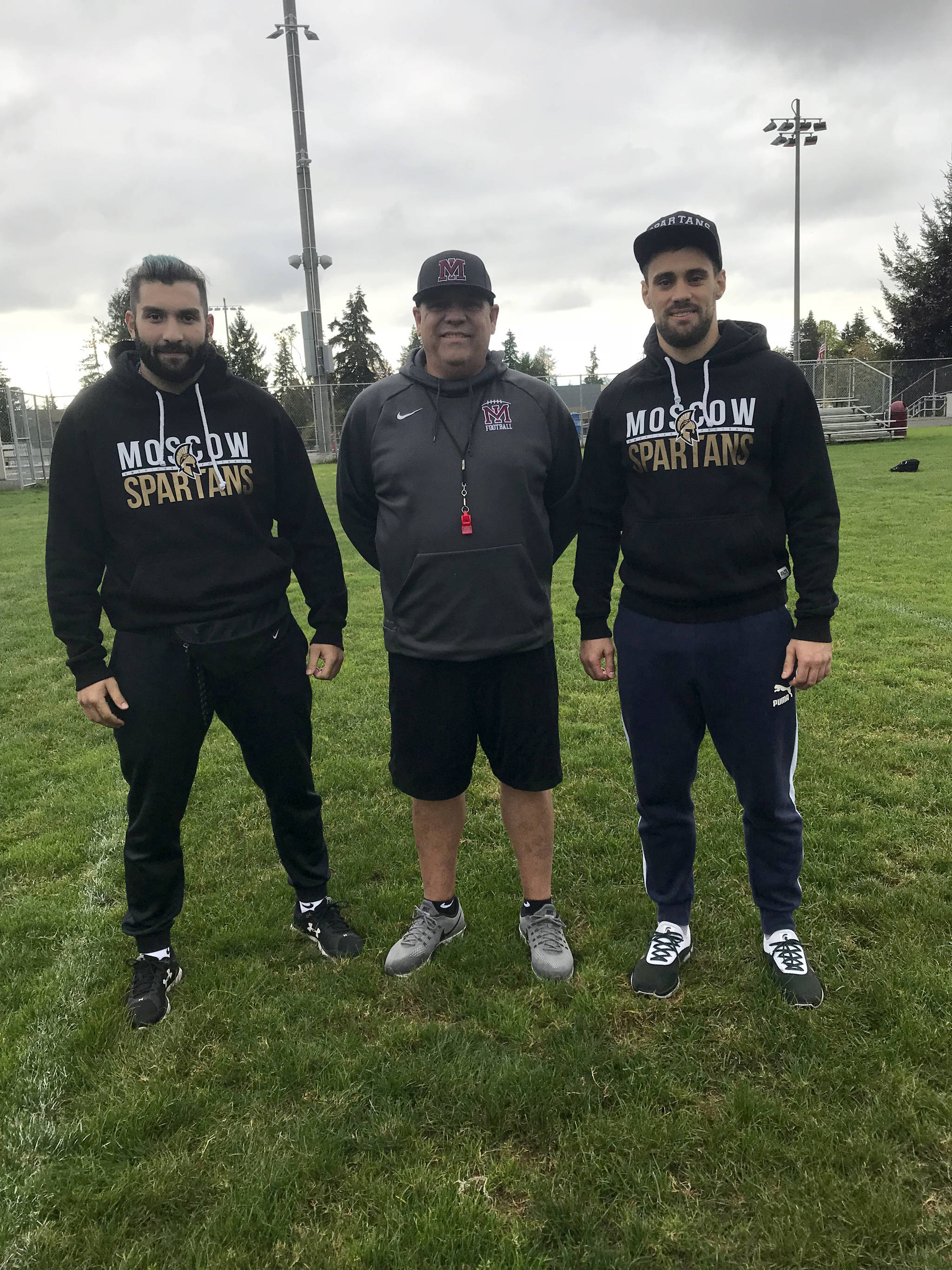 Moscow Spartans football players Omari Grinyaev, Michael Levenshtein and Mercer Island head football coach Ed Slezinger pose for a quick photo prior to the start of Mercer Islands football practice on Oct. 9. Grinyaev and Levenshtein will be in Washington observing the Islanders football programs practices, meetings, workouts and games through Oct. 22. Shaun Scott/staff photo