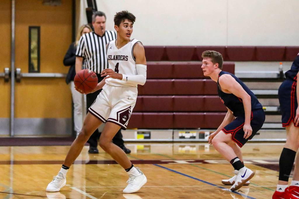 Mercer Island Islanders junior Adam Parker, left, looks for a teammate to pass to against the Juanita Rebels. Parker finished with a team-high 20 points against the Juanita Rebels on Dec. 11. The Islanders defeated the Rebels 56-49. Photo courtesy of Rick Edelman/Rick Edelman Photography