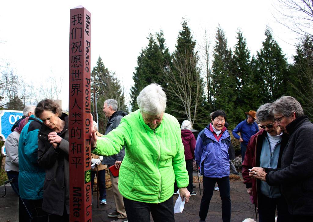 Mercer Island resident Kathy Finn places a hand on the peace pole at Covenant Shores on Jan. 18. Katie Metzger/staff photo