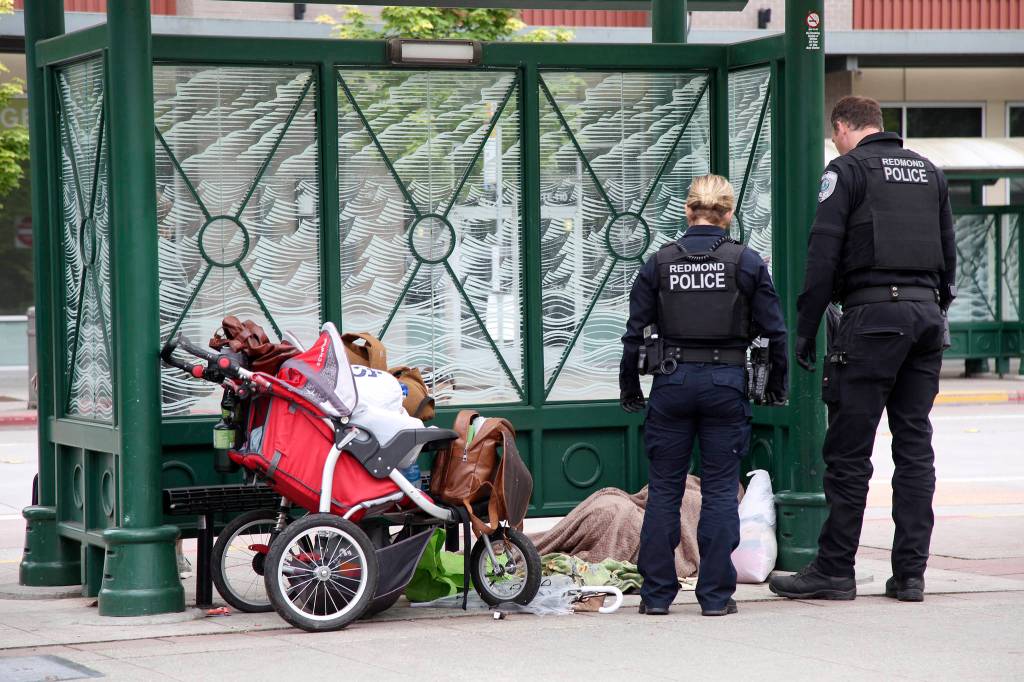 Redmond Police Officers and Kroll (not pictured) make contact with an individual sleeping at the downtown park and ride center. Ashley Hiruko/staff photo