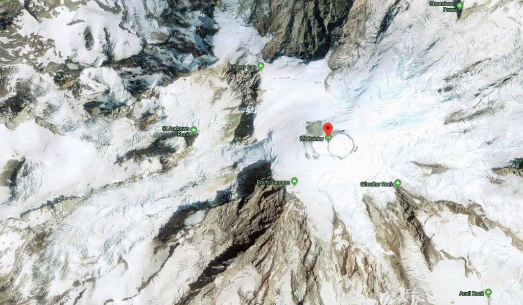 An aerial photo of Mount Rainier. The rescued climbers were found between Liberty Cap, the mountains smallest peak, and Columbia Crest, its tallest, marked with the red pointer. Image courtesy Google Maps
