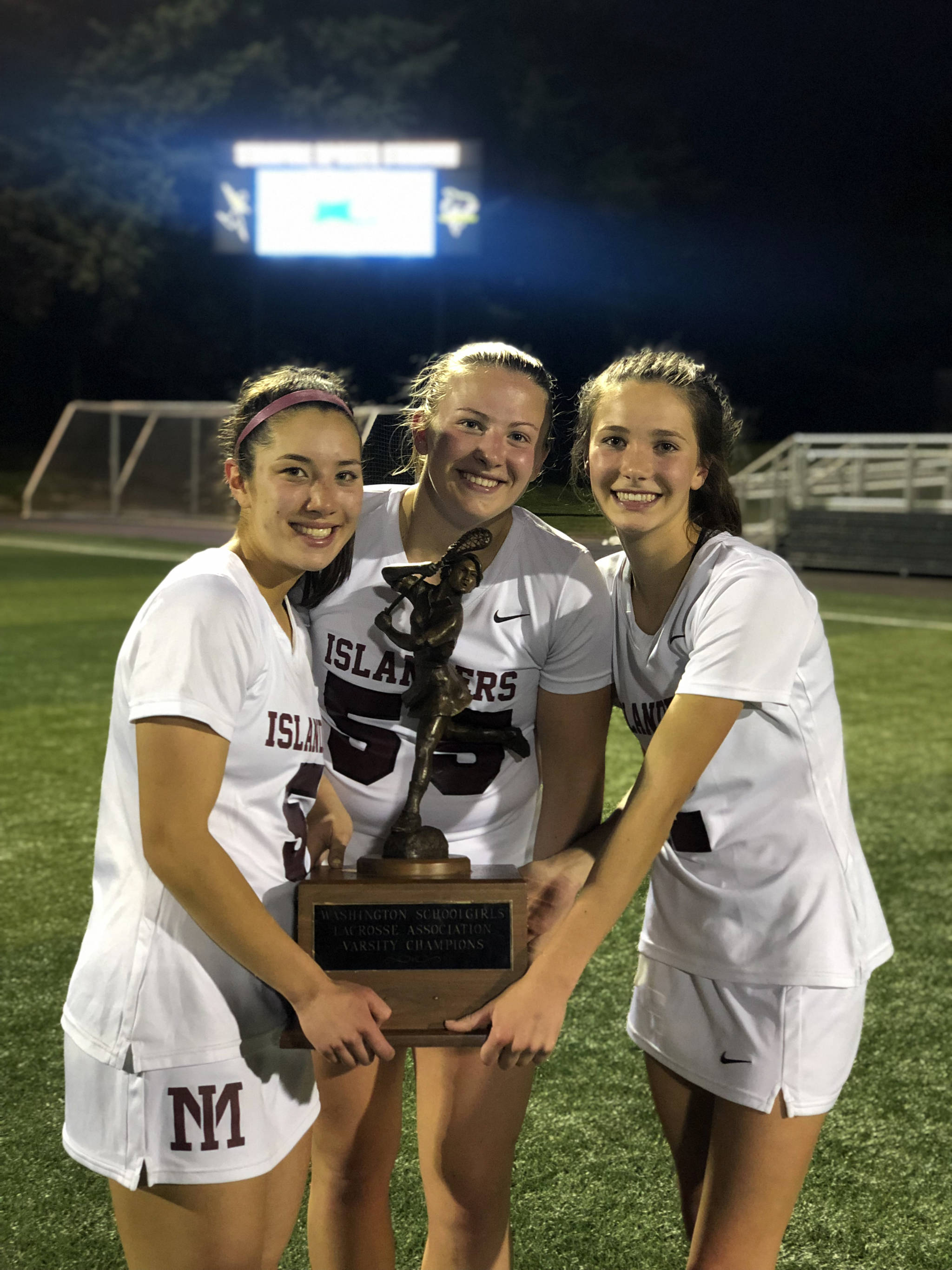 Mercer Island girls lacrosse players Grace Fujinaga, Annabelle Gersch and Hannah Tiscornia hold the state championship trophy following their 10-9 victory against Bainbridge Island in the Washington Schoolgirls Lacrosse Association championship game on May 17. Photo courtesy of Kathy Gersch