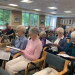 Mercer Island seniors sing from their songbooks in the Fellowship Hall at Covenant Living at the Shores on July 17. Madeline Coats/staff photo                                 Pastor Greg Asimakoupoulos and Rotarian Karen Dunning guided the group through 15 songs during the sing-a-long program. Madeline Coats/staff photo