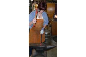 Author Claire Gebben gives blacksmithing a go at Bruce Weaklys private shop on Whidbey Island. Gebben sought to learn the art of blacksmithing to better understand the life of her great-great grandfather, who immigrated to Cleveland in the mid-1800s. Photo courtesy of Claire Gebben