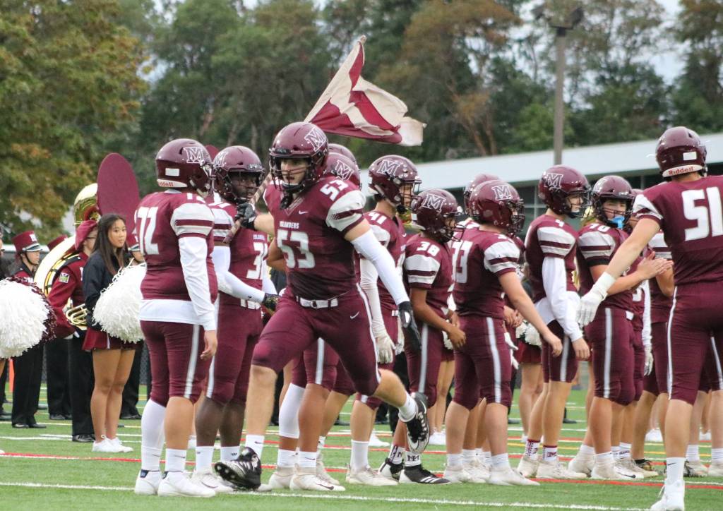 Mercer Island defensive tackle and guard, Bryce Fitzwilson, runs onto the field carrying a flag before the game on Sept. 13. Benjamin Olson/ staff photo