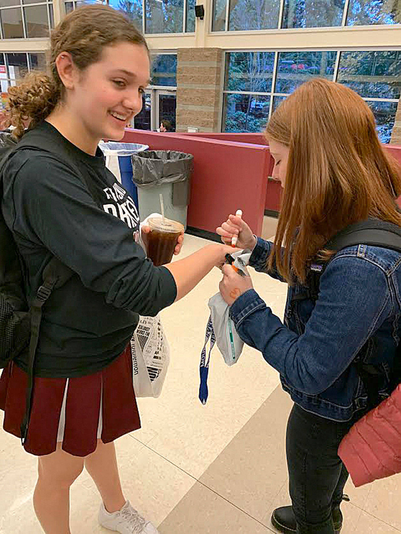 Bella Hartman draws orange hearts on Sophie Gottesmans hand for her refugee awareness day at MIHS on Nov. 15. Courtesy photo