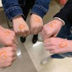 Natalie Dumler, Justin Weiss and Bella Hartman show their support for refugees through wearing orange hearts on Nov. 15. Courtesy photo