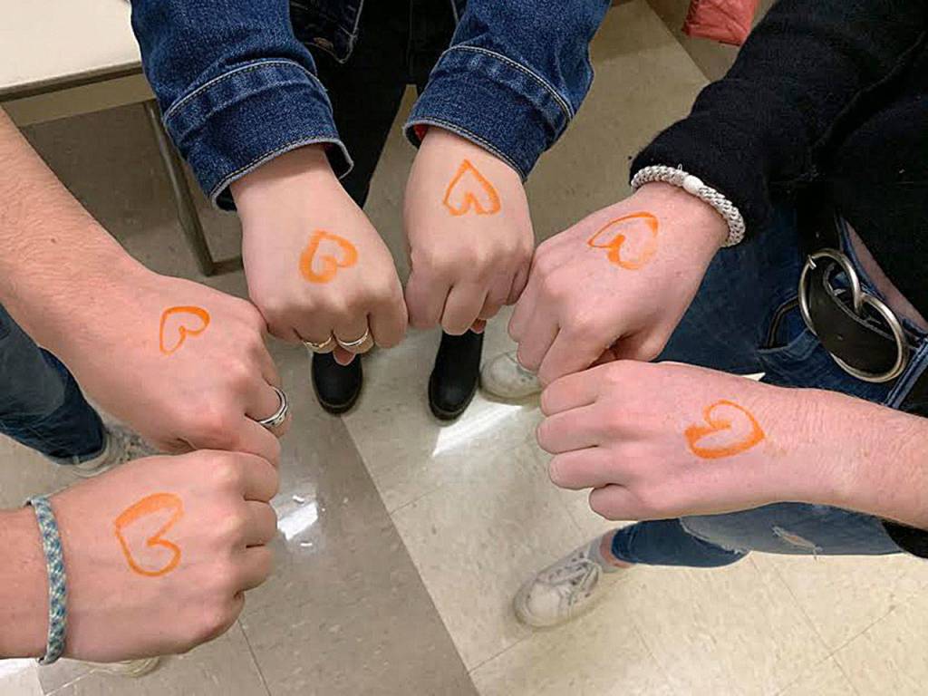 Natalie Dumler, Justin Weiss and Bella Hartman show their support for refugees through wearing orange hearts on Nov. 15. Courtesy photo