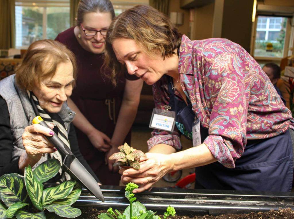Courtesy photo                                Eldergrow program administrator Katy Dittmer works with Covenant Living at the Shores resident Althea Esterley at the communitys new indoor mobile sensory garden during at Jan. 17 kickoff event.
