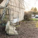 The old East Seattle Elementary School building boarded up and surrounded by various discarded items and trash.