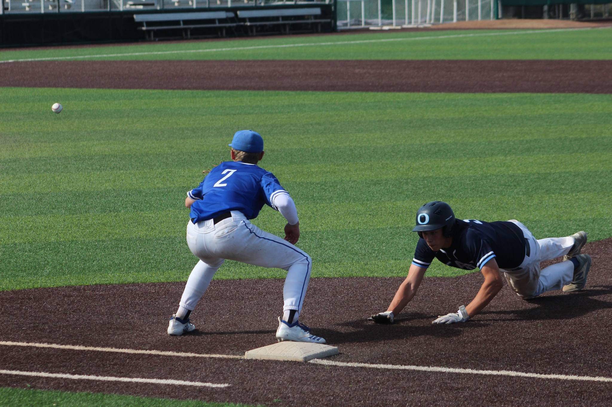 Federal Ways Jack Arsenian anticipates a catch as an Olympia player leaps back to first base at the state quarterfinals in in Everett in May 2019. Olivia Sullivan/staff photo
