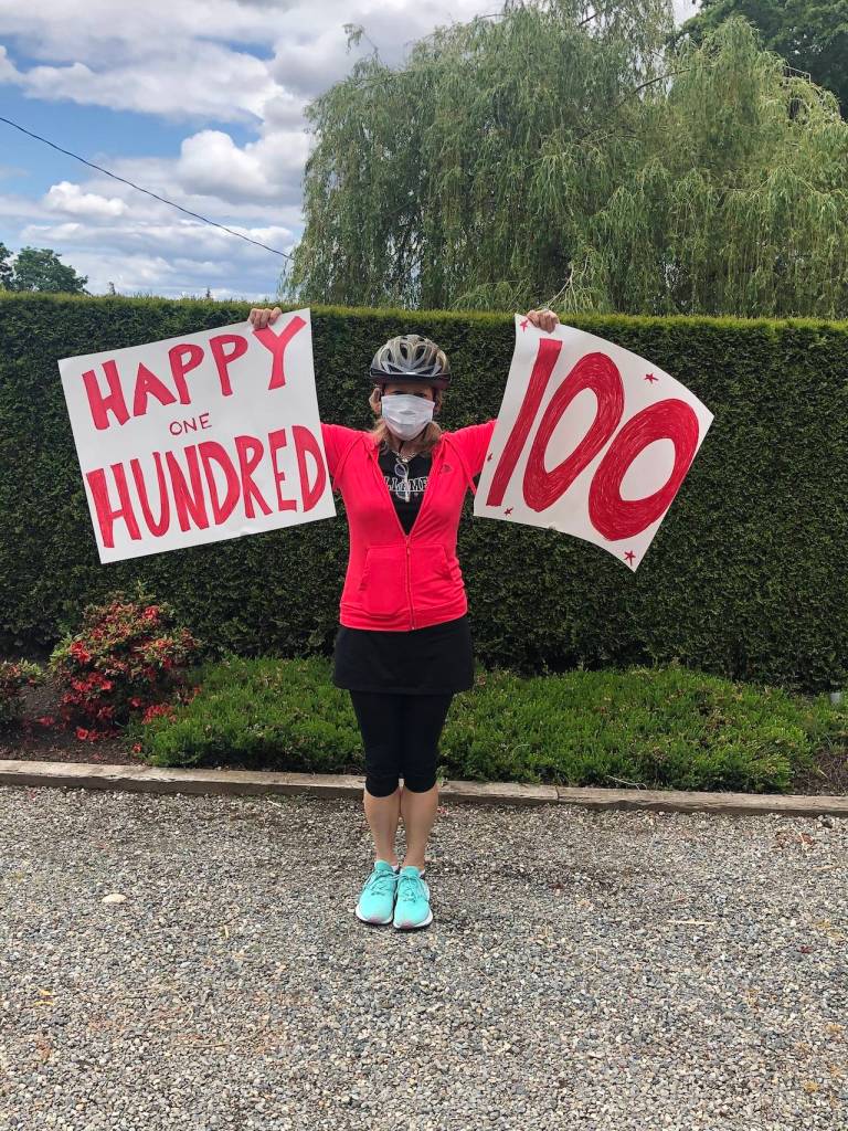 A neighbor holds signs wishing Jamerson a happy 100th. Photo courtesy Julie King Hately