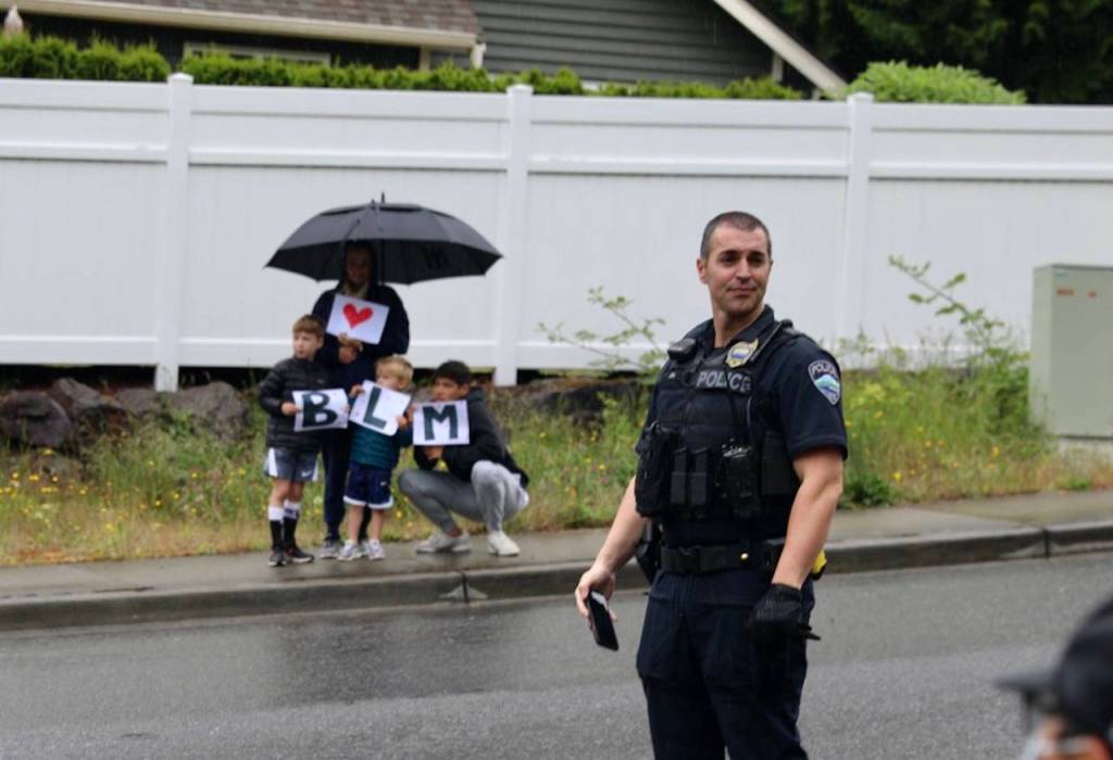 A police officer standing by as a family looks on. Blake Peterson/staff photo