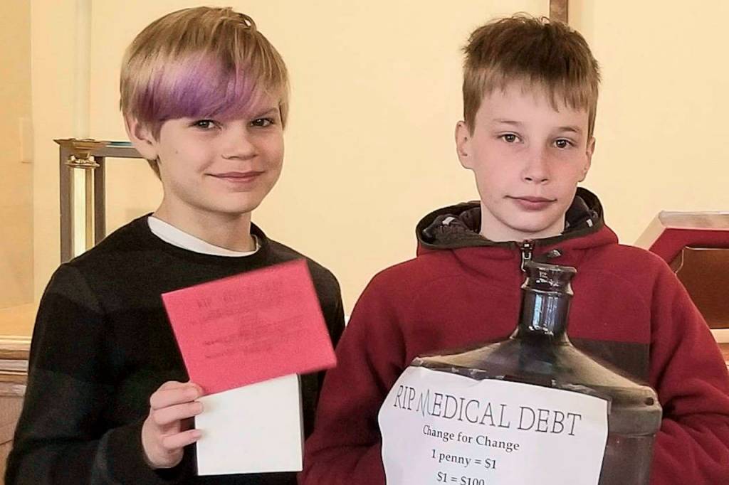 Brody Newcomer (left) and Matthew Duffie, two Sunday school children at Holy Trinity Lutheran Church on Mercer Island, pose with a change collection bank for the churchs Lent fundraiser with RIP Medical Debt earlier this year. The churchs youths, according to director of Intergenerational Ministry Programs Kathy Fisher, were integral to fundraising efforts. Photo courtesy HTLC