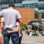 Ryan Murphy holds his daughters, Peyton, Teegan and Paisley, as they pay their respects Tuesday to the Bothell police officer who was killed Monday night. (Olivia Vanni / The Herald)
