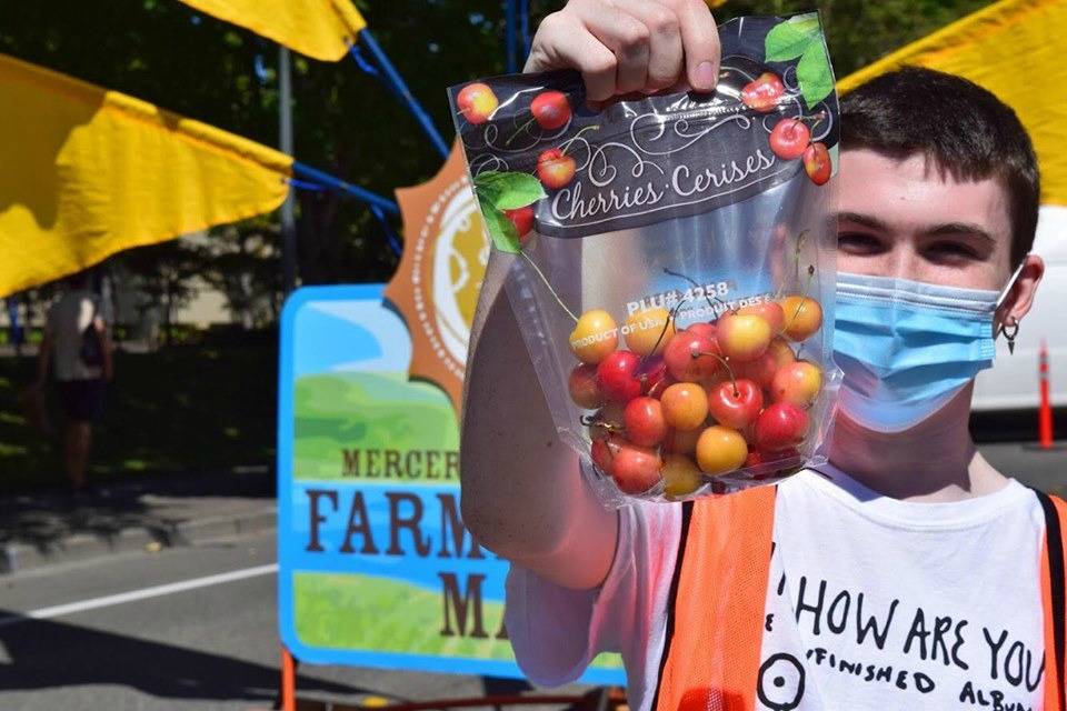 Mercer Island Farmers Market staff member Elliot Jester displays some cherries. Photo courtesy of the Mercer Island Farmers Market