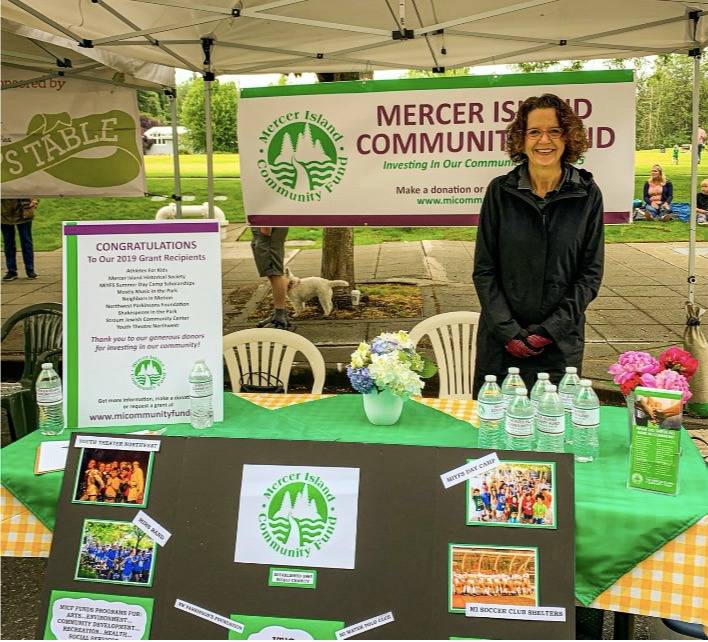 Mercer Island Community Fund board member Sarah Cox represents the fund at a table at the Mercer Island Farmers Market, pre-COVID. Photo courtesy of Erin Siriannis My MI blog