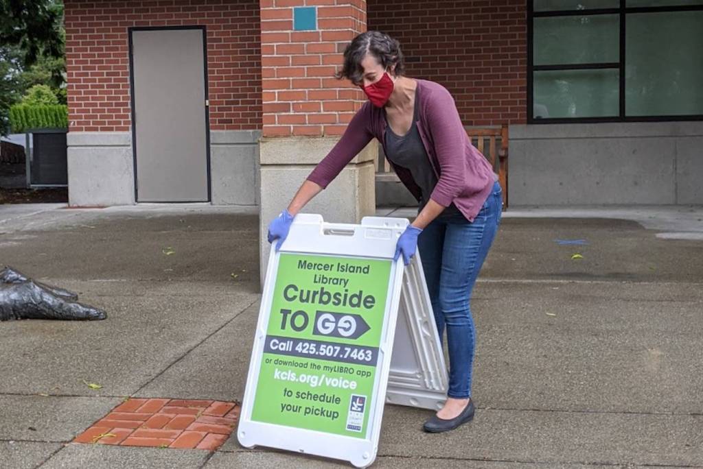 A library staffer setting up a Curbside to Go sign. Photo courtesy KCLS