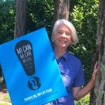 Callie Ridolfi displays one of the Mercer Island Climate Action Now (MI CAN) signs that have been widely distributed on the Island. Photo courtesy of Bruno Ridolfi