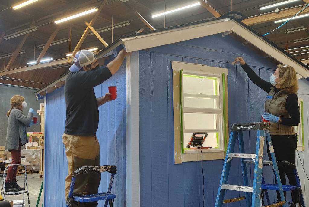 From left, Angela McCann, Ali Mastan and Kelly Thilen paint a tiny house as part of Amazon Web Services volunteer effort on Jan. 15. Andy Nystrom/ staff photo