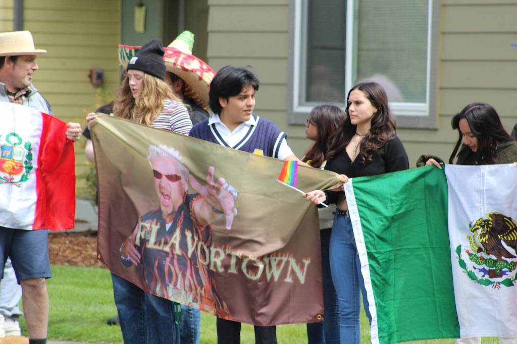 Directly across the street from a crowd holding pro-Trump and anti-Biden signs, members in this crowd hold flags representing the nations of Peru, Flavortown and Mexico, as well as a miniature rainbow pride flag. Photo by Alex Bruell/Sound Publishing