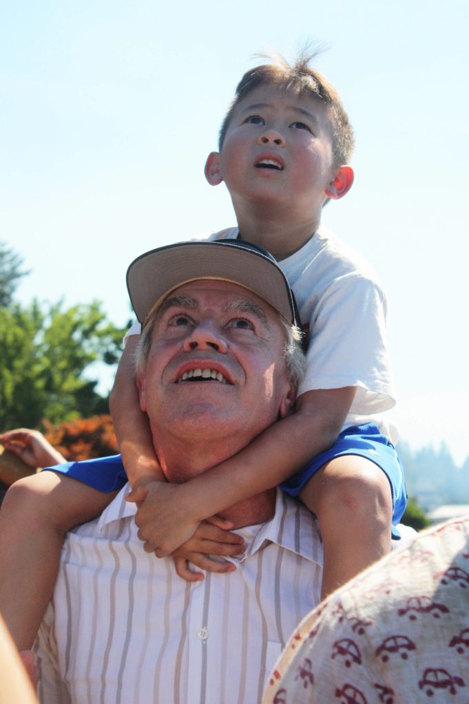 Matthew Mar, 6, of Bellevue watches the Blue Angels on Sunday atop the shoulders of his grandpa, Kevin Gregerson of Bellevue, on the Groveland Beach Park pier on Mercer Island. Andy Nystrom/ staff photo