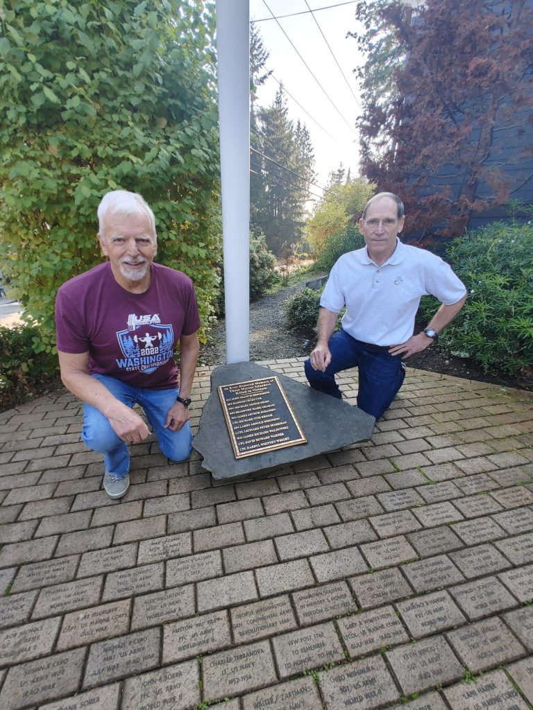 From left, Bob Harper and Thomas Koger kneel in Patriots Plaza, which features pavers honoring local veterans and a memorial plaque to remember those Islanders who were killed in Vietnam. Andy Nystrom/ staff photo