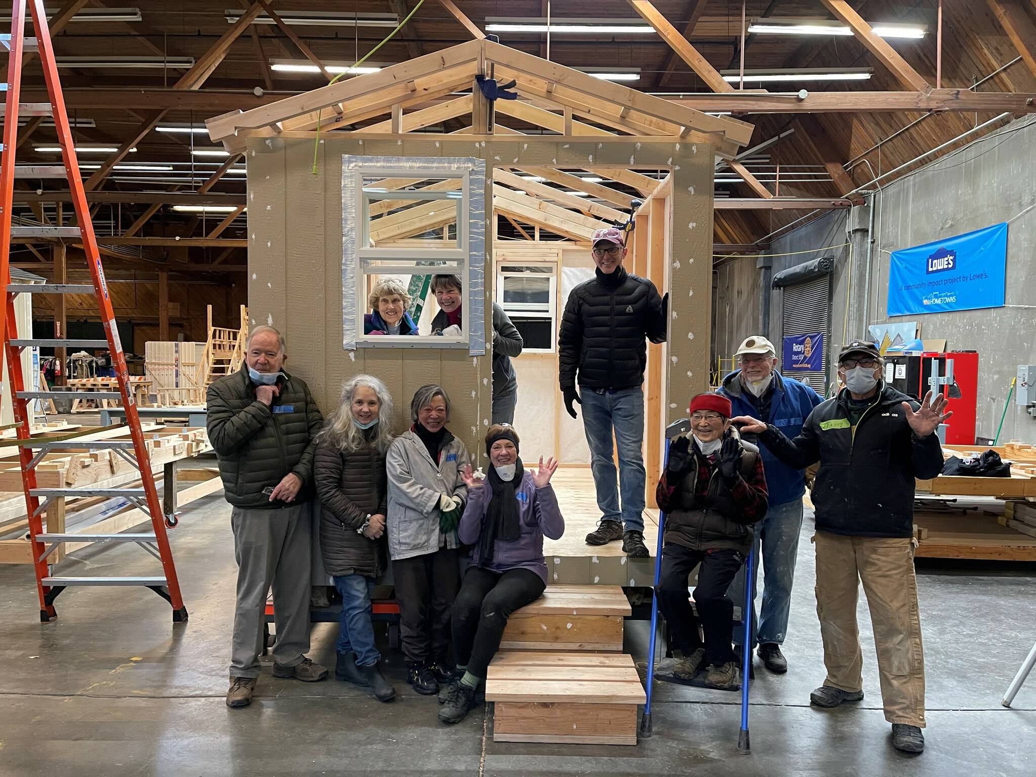 Pictured Mercer Island Rotarians at a tiny houses for the homeless building event in Seattle last year are Bunnie Cundiff (sitting on stairs); Edie Warner (in window to the right); Mike Finn (standing, second from right); and Terry Lee (farthest right). Courtesy photo