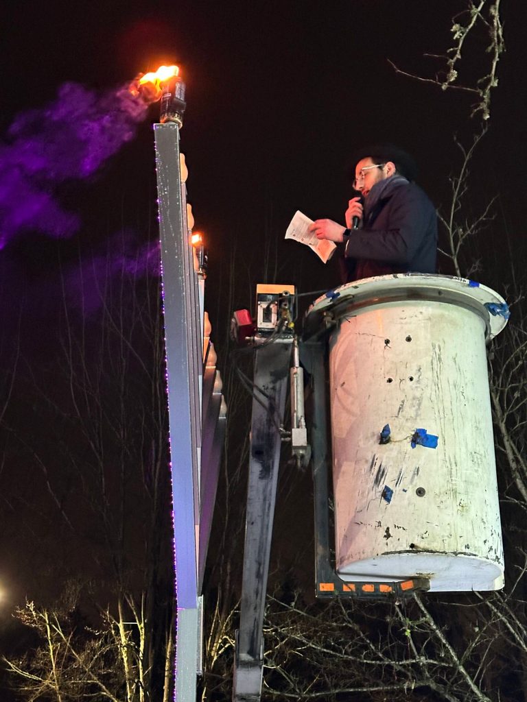 More than 250 people came to the menorah lighting celebration at Mercerdale Park on Dec. 7, the first of the eight days of Chanukah. Rabbi Nissan Kornfeld of Chabad Mercer Island used a bucket lift to reach the top of the 12-foot menorah and light first the middle flame, then one on the right. Chanukah, the Festival of Lights, recalls the victory of more than 2,100 years ago of a militarily weak but spiritually strong Jewish people over the mighty forces of a ruthless enemy that had overrun the Holy Land and threatened to engulf the land and its people in darkness, said the printed programs prepared by Chabad. A little light expels a lot of darkness. The family-friendly gathering featured live music, hot apple cider, balloon tying, a dreidel game, prayers, blessings and group songs such as Chanukah, Oh Chanukah, come light the Menorah. Lets have a party, well all dance the hora. About 20% of Mercer Island residents are Jewish, and recent antisemitic incidents on the Island made this years event especially important, many participants said. Photo courtesy of Greg Asimakoupoulos