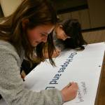 Mercer Island High Schools Nadia Slivinski, left, and Anna Mock jot down their thoughts on the Our Hopes and Dreams for Mercer Island Youth banner at the MI Healthy Youth Forum 2022. Some of the messages were, strong, passionate, caring, empathetic, understanding, loving and responsible, loving, kind. Andy Nystrom/ staff photo