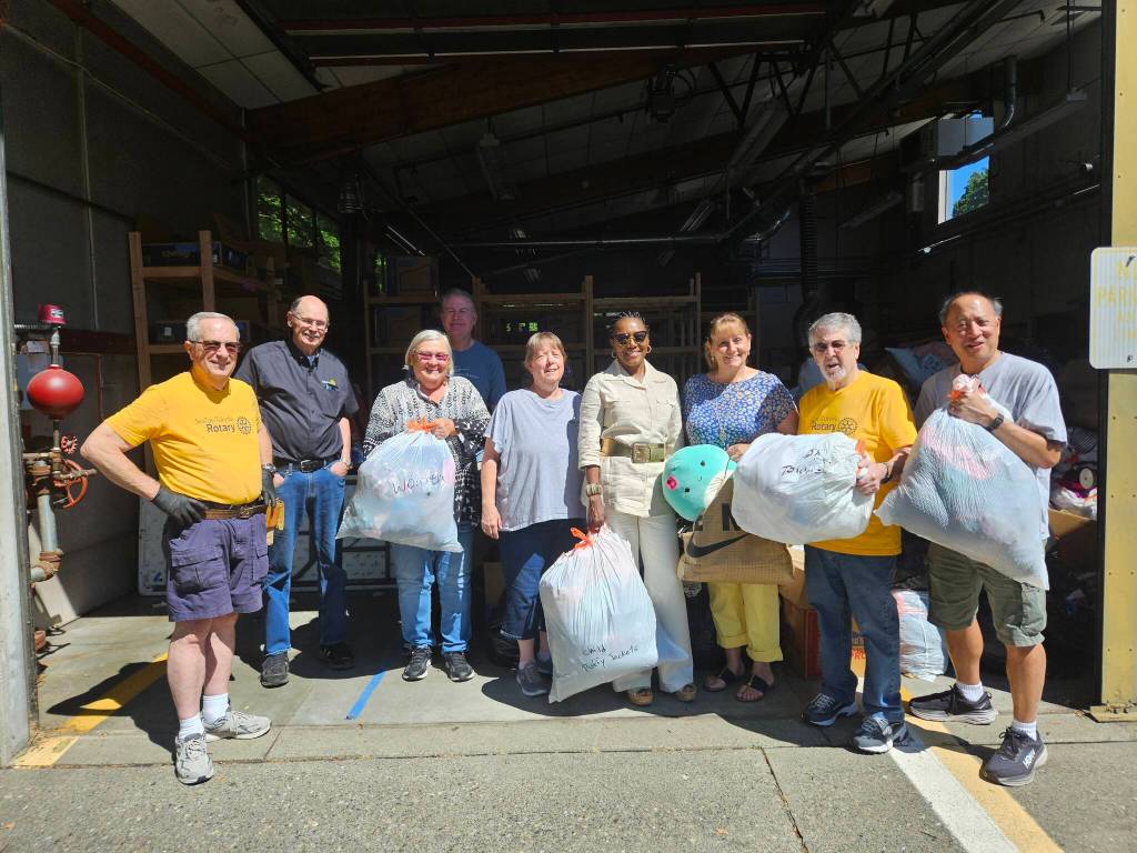 Rotarians from Mercer Island took almost 50 bags and boxes of kids clothing to Tukwila on Aug. 1. From left: Dave Bush, Randy Coplen, Claudia Dickinson, Bonnie Lusby of Tukwila Rotary, Novelett Cotter of MI, Katrina Dohn and Mel McDonald of Tukwila, Benson Wong of MI. In back row, Todd White of MI. (Photo by John Hamer)