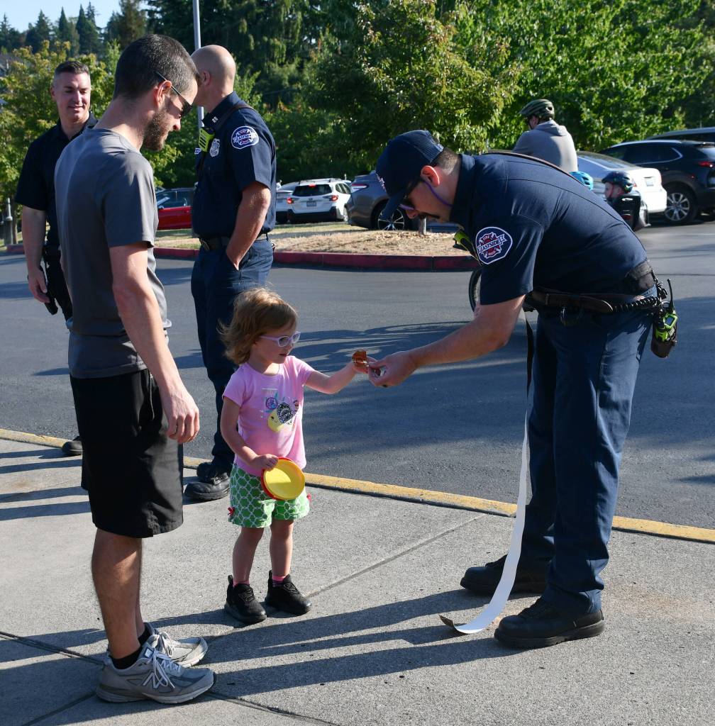 Eastside Fire & Rescues Josh Stalker gives Viki Younger, 3, a National Night Out sticker while her dad Robert watches on Aug. 6 at the Mercer Island Community and Event Center. Andy Nystrom/ staff photo