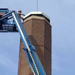 A worker positions a steel roof cap on the chimney of the Luther Burbank Park boiler building. Photo courtesy of the city of Mercer Island