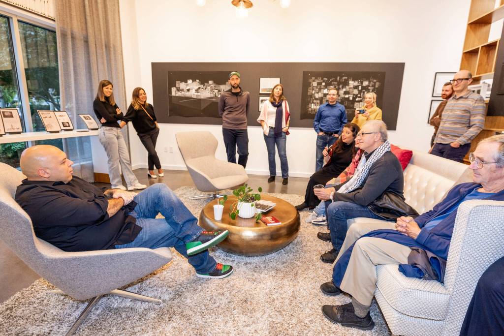 Amer Zahr (left), a Palestinian Arab American comedian, speaker, writer, academic and adjunct professor at University of Detroit Mercy School of Law, meets with attendees at the SZ Gallery on Oct. 11 on Mercer Island. Also pictured is a portion of the Control Anatomy exhibit by Palestinian artist Mahmoud Alhaj. Photo courtesy of Flora Art Life