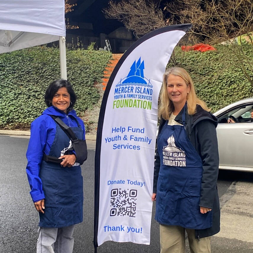 At the city of Mercer Island recycling event on March 29, Mercer Island Youth and Family Services (MIYFS) Foundation board members and volunteers collected more than $6,000 in monetary and gift card donations to support MIYFS food security programs. People coming to recycle and donate were able to spot volunteers in blue aprons and a flag with the foundation logo. Its amazing how many residents remember to come prepared to support Islanders in need at this twice a year event with checks, cash and gift cards in hand to pass along to volunteers before they head over to the recycling facilities, the foundation said. Pictured are, from left, community volunteer Karen Ramsahai and MIYFS Foundation board member Jocelyn Barber. Photo courtesy of Lisa Swanson