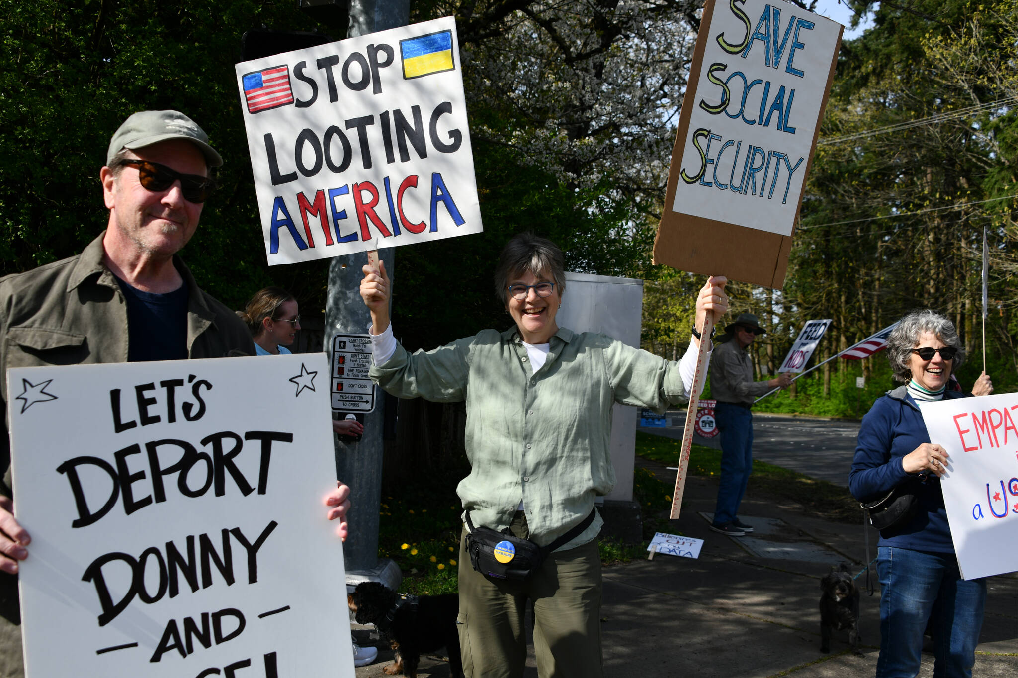 Gene Robertson, center, has spearheaded the Mercer Island peaceful protests against the United States government. Here, she joins protesters on April 13 at the intersection of Island Crest Way and Southeast 40th Street. Protesters stood and waved signs on all four corners. Andy Nystrom/staff photo