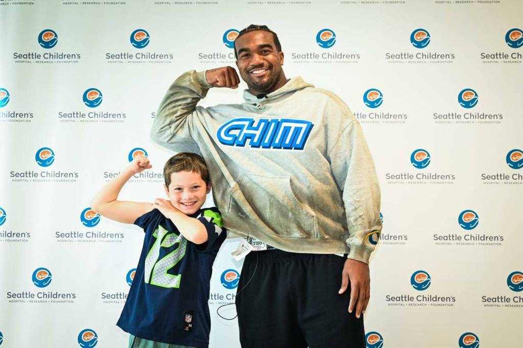Emerson Vivion flexes his muscle with former Seattle Seahawk Tyrel Dodson. (Photo courtesy of the Seattle Seahawks)