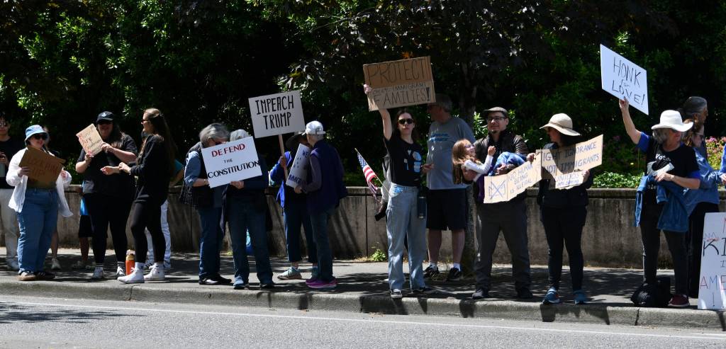 Mercer Island No Kings rally attendees display their signs along 78th Avenue Southeast in front of Mercerdale Park. Andy Nystrom/ staff photo